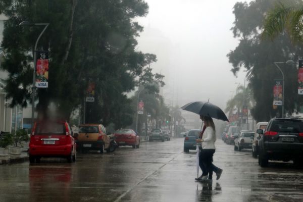 Personas cruzando una calle con un paraguas en un día de lluvia en Punta del Este.