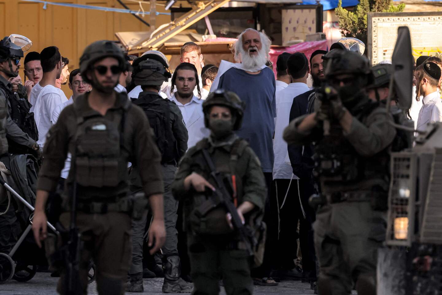 Soldados israelíes hacen guardia mientras colonos israelíes recorren el casco antiguo y el mercado de la ciudad palestina de Hebrón, en la Cisjordania ocupada, el 28 de junio de 2025.