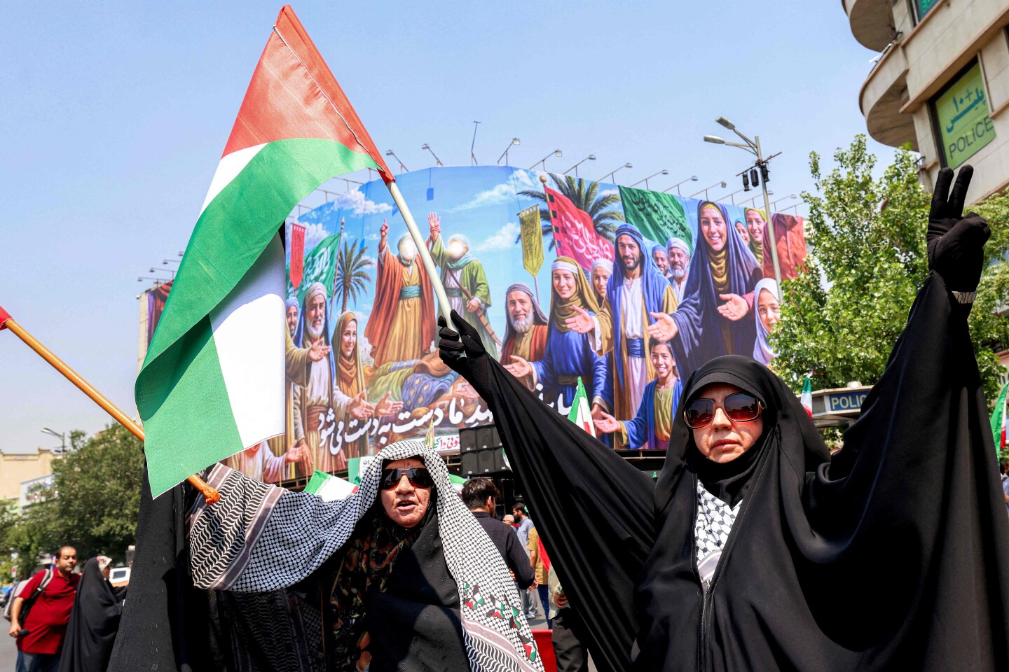 Una mujer sostiene una bandera palestina y otra, una iraní, mientras la gente se congrega para protestar contra la oleada de ataques israelíes contra Irán en la plaza Enghelab (Revolución), en el centro de Teherán, el 13 de junio de 2025.