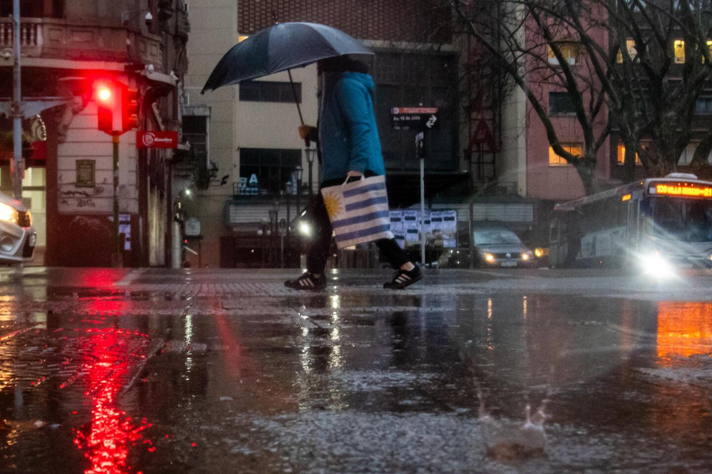Una persona camina con paraguas un día de lluvia en Montevideo.