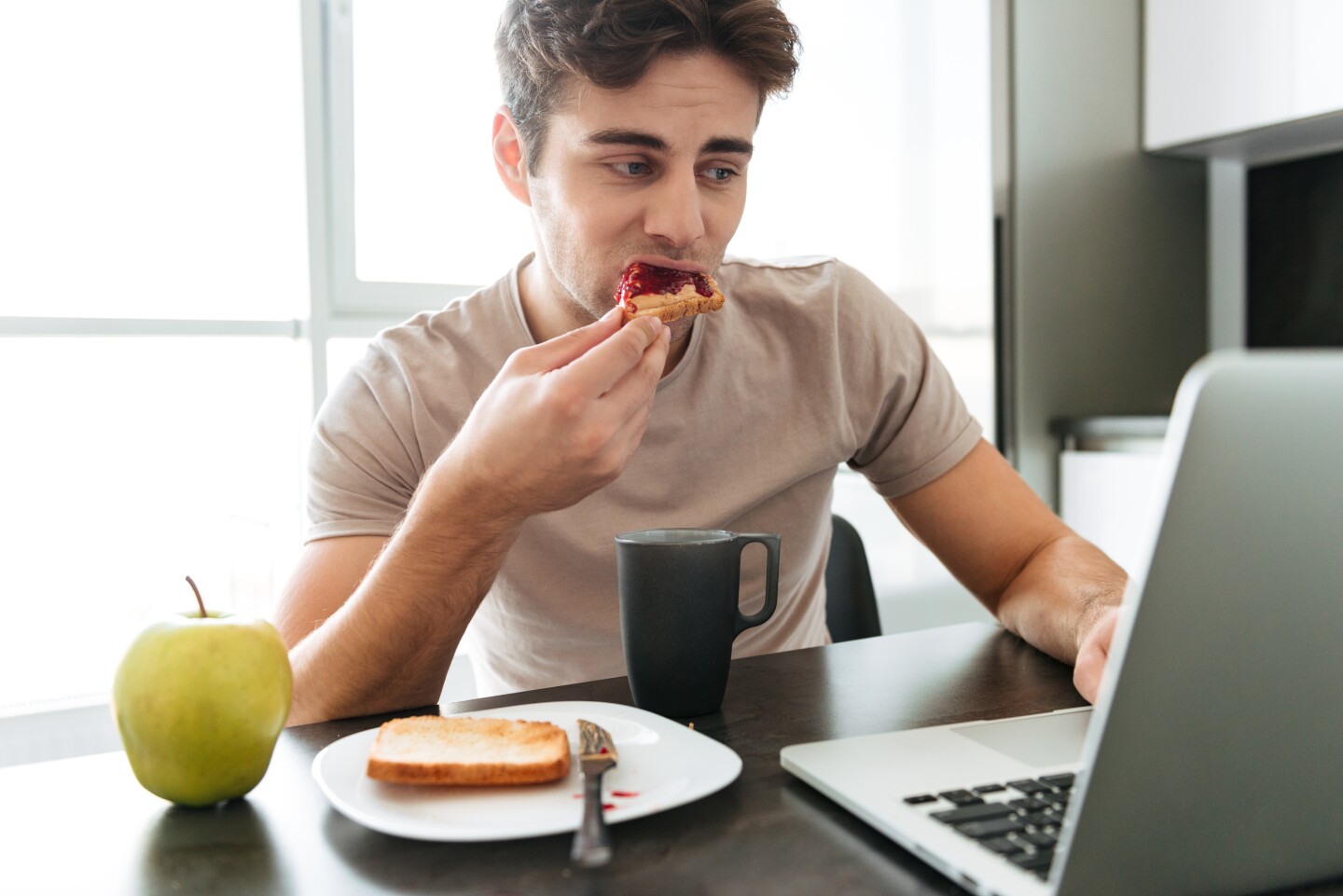 Hombre desayuna frente a la computadora