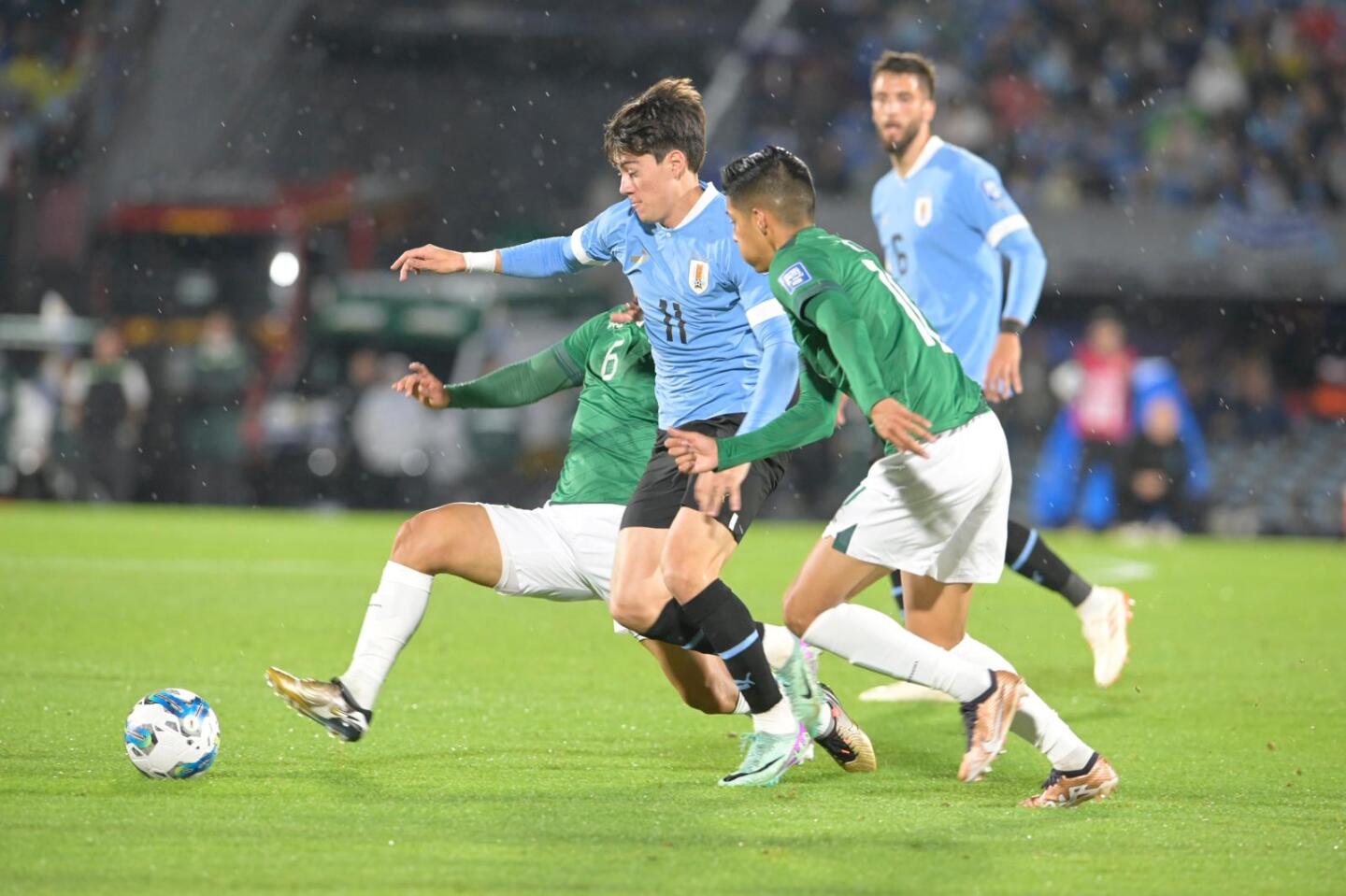 Facundo Pellistri se lleva la pelota ante dos futbolistas bolivianos.