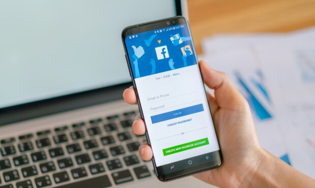 Una persona sostiene un celular con la aplicación Facebook.