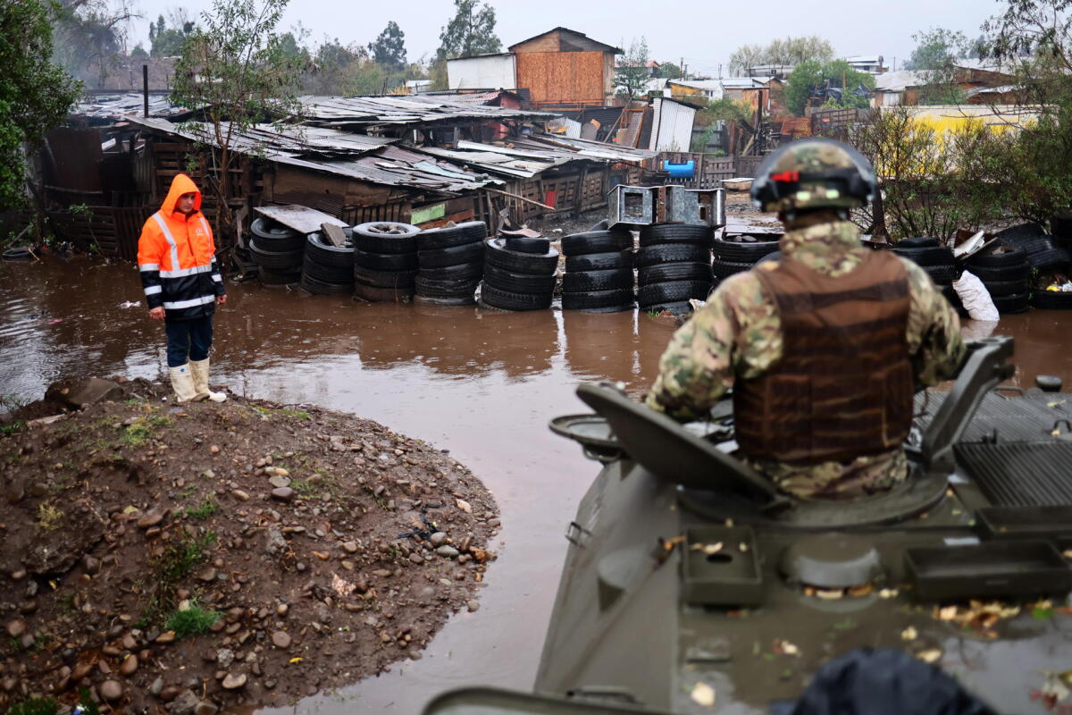 Integrantes del Ejercito de Chile evacúan un campamento que presenta riesgo de inundación por el temporal este viernes, en la rivera del río Mapocho en Talagante.