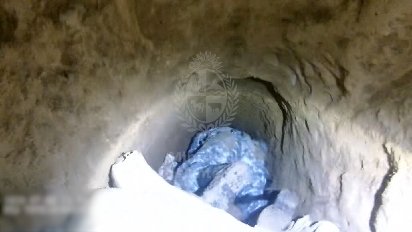 Agente policial ingresando al túnel cavado por delincuentes en Ciudad Vieja