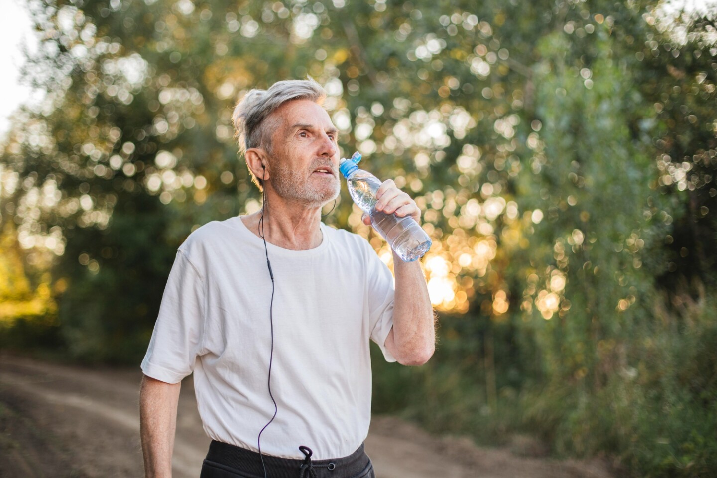 Hombre de mediana edad tomando agua mientras hace ejercicio