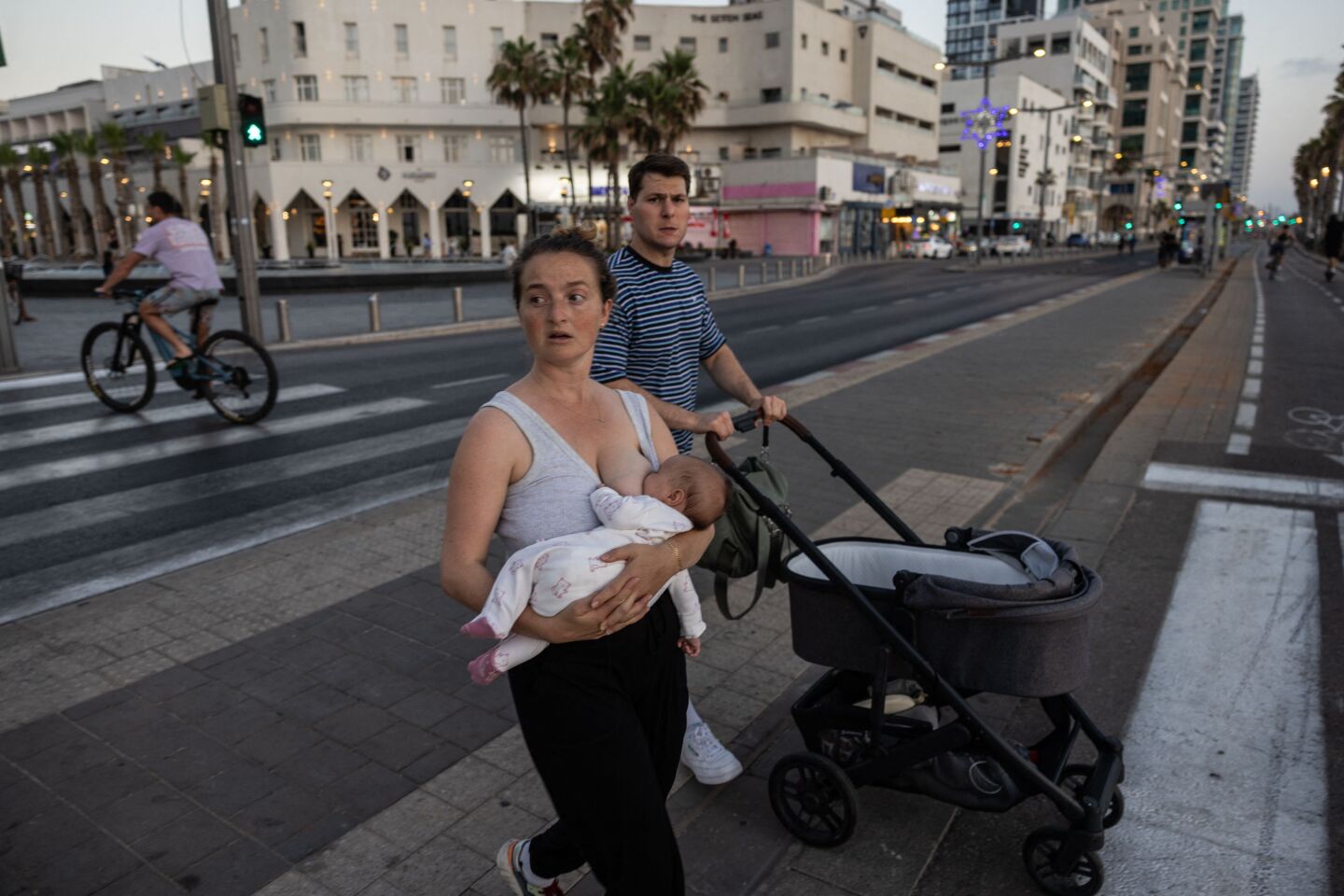 Una mujer amamanta mientras camina por la orilla del mar en el centro de Tel Aviv el 16 de junio de 2025, en medio de la escalada del conflicto entre Israel e Irán.