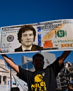 Un militante del presidente electo Javier Milei muestra un cartel con un billete de cien dólares con una imagen del futuro presidente mientras espera afuera del Congreso.