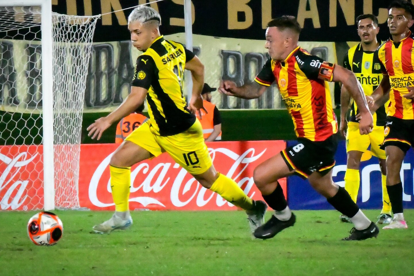 Leonardo Fernández se lleva la pelota ante la marca de Adrián Colombino en el partido entre Progreso y Peñarol en el Estadio Centenario.