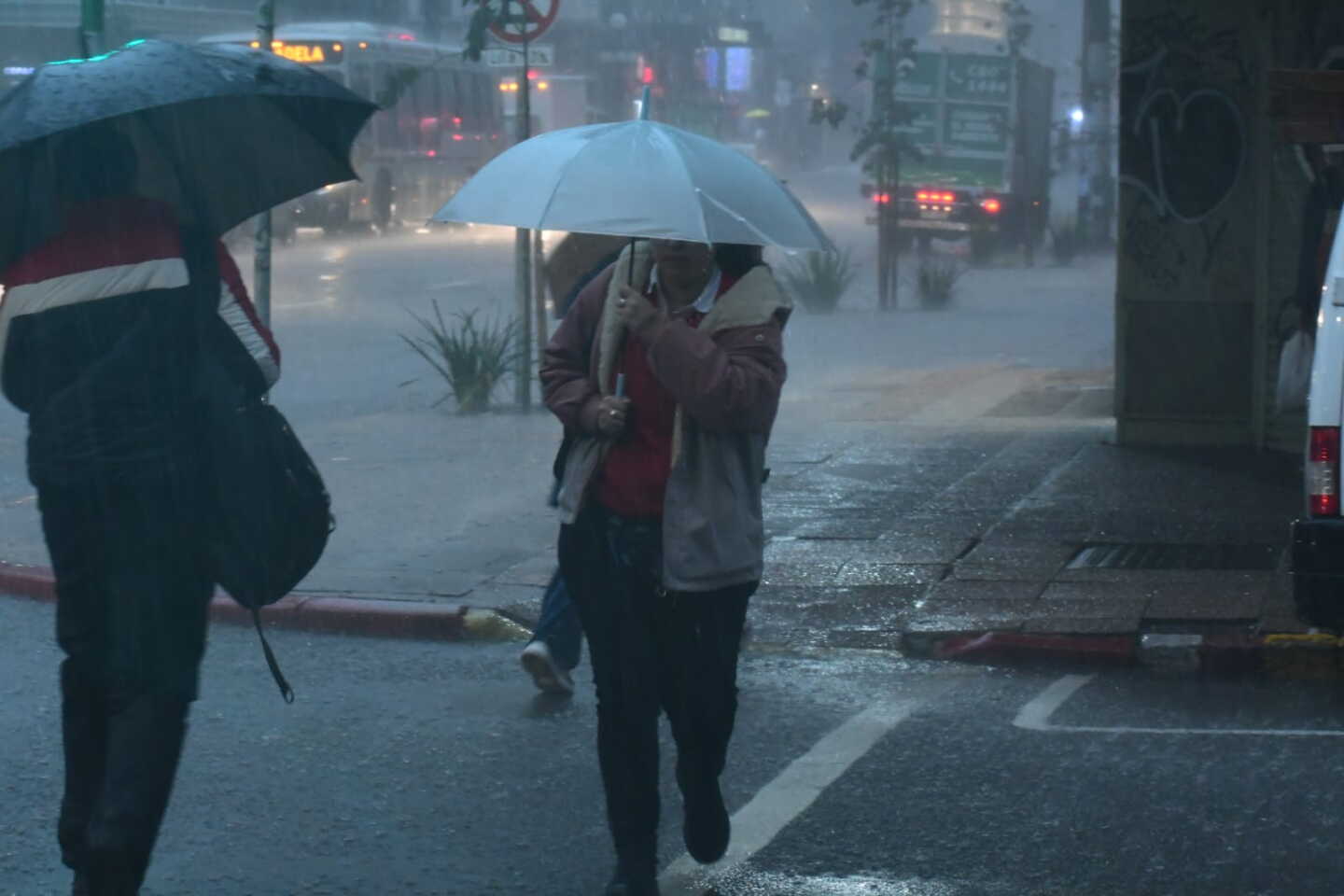 Mujer camina con un paraguas por 18 de Julio un día de lluvia.