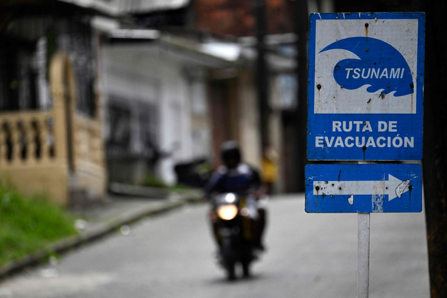 Un motociclista pasa junto a una señal de ruta de evacuación por tsunami durante una alerta de tsunami en Buenaventura, departamento del Valle del Cauca, Colombia.