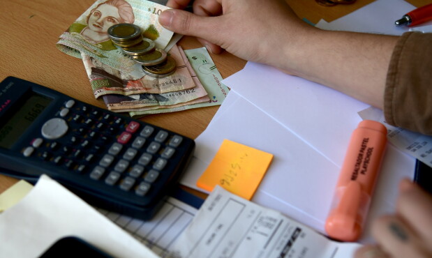 Persona con una calculadora, varios billetes y facturas. Foto: Estefanía Leal.