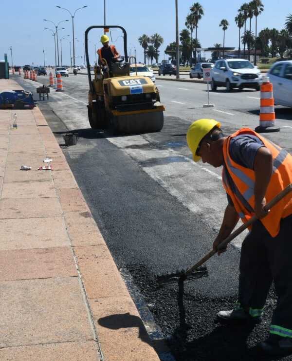 Funcionario con un rastrillo trabaja en la construcción de la ciclovía de la rambla de Montevideo.