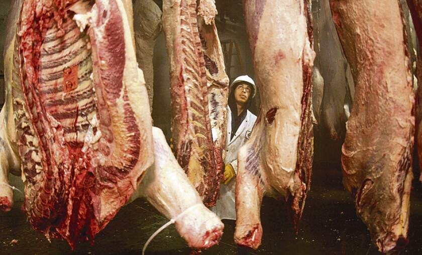 ** FILE ** Felipe Murillo seperates sides of beef as they cool at the