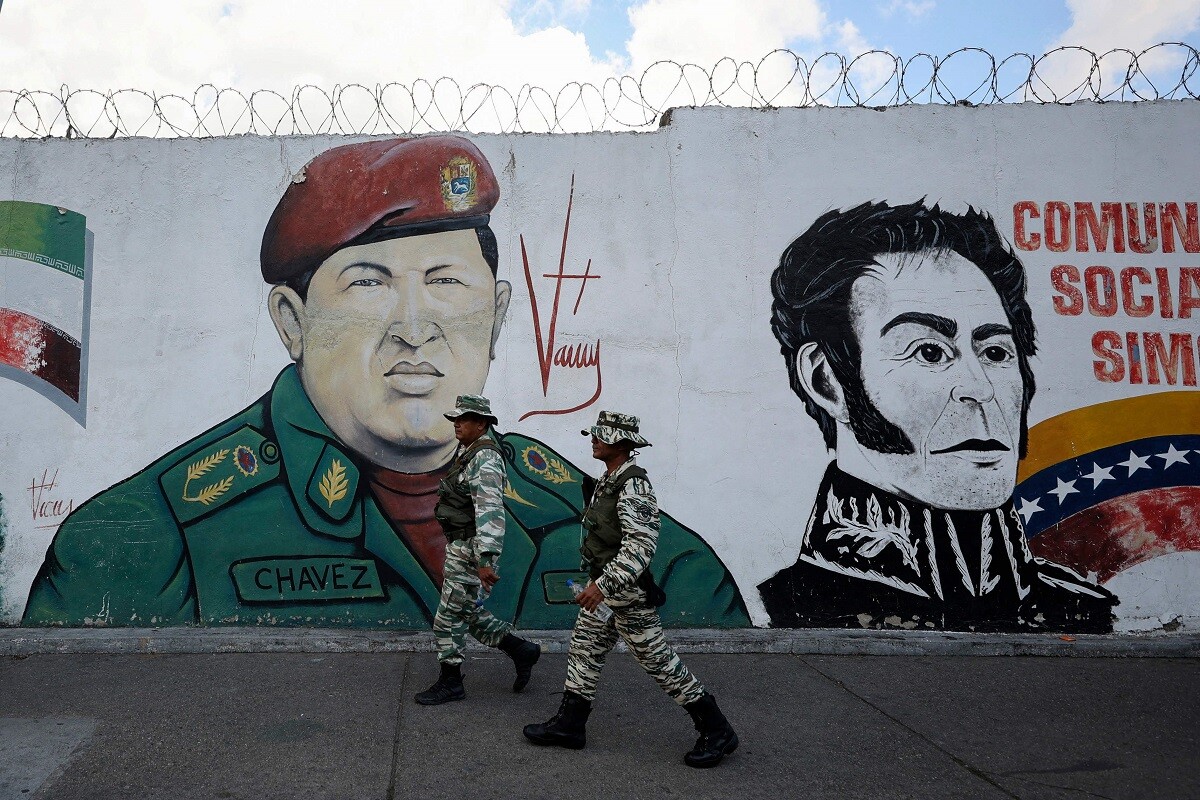 Dos miembros de la milicia bolivariana pasan junto a un mural con la imagen del fallecido presidente venezolano Hugo Chávez y el libertador venezolano Simón Bolívar