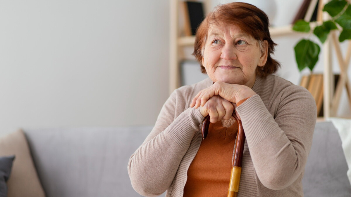 Adulta mayor sentada con su bastón.