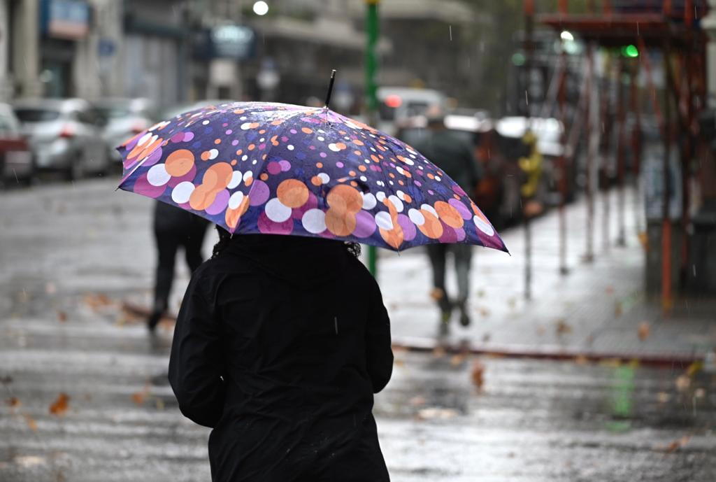 Una persona se refugia de la lluvia bajo un paraguas en Montevideo