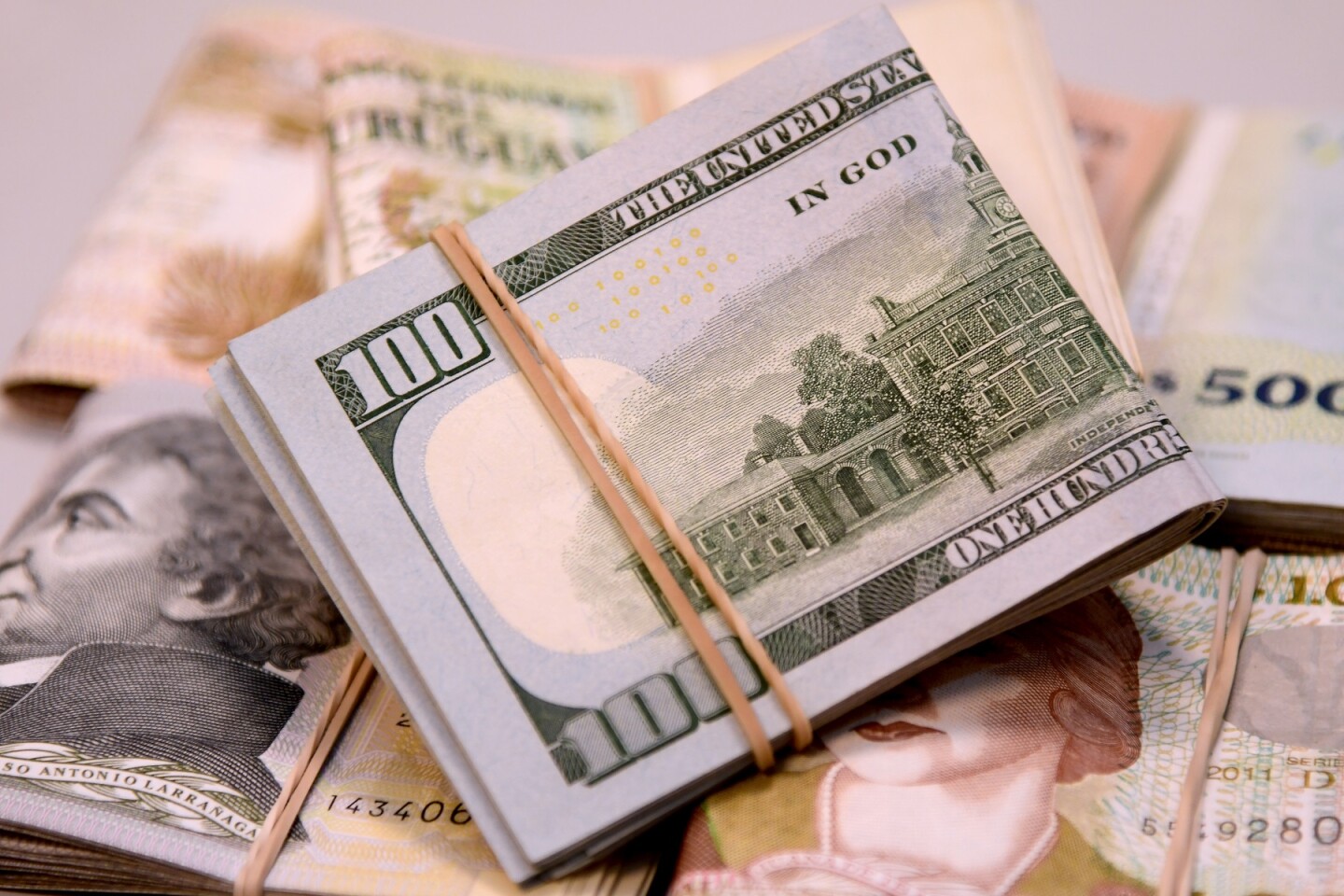 Billetes de 100 dólares estadounidenses y de 1.000 y 2.000 pesos uruguayos.