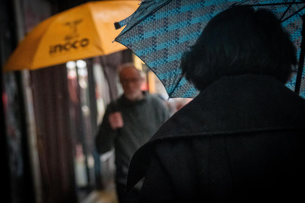 Gente con paraguas caminando por Av. 18 de Julio en el barrio Centro en día de lluvia en la ciudad de Montevideo.