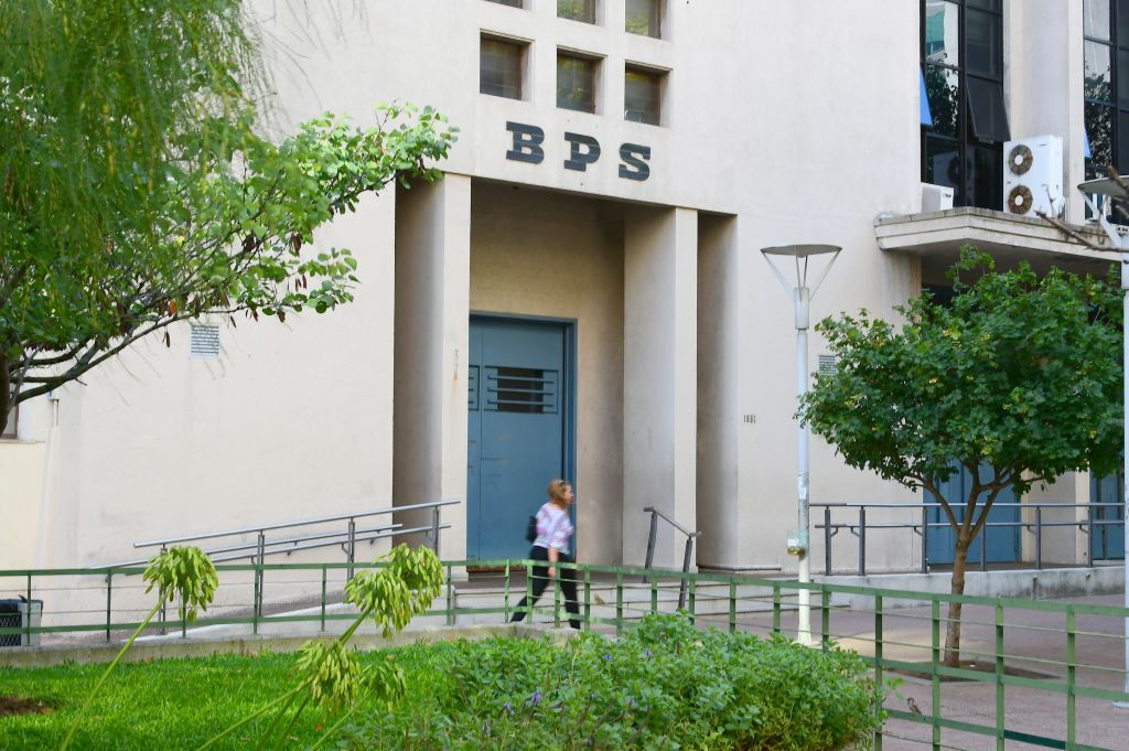Una mujer pasa caminando frente a la puerta de la sede del Banco de Previsión Social (BPS).