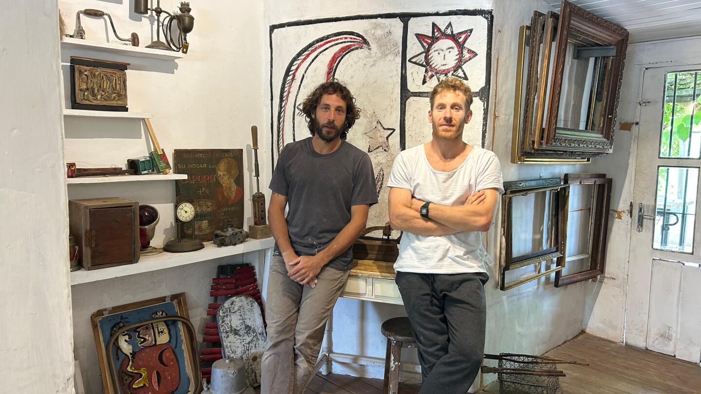 Matías e Ignacio Choroszczucha en "Casa Las Grutas", y de fondo, el mural que pintó Páez Vilaró en los noventa.