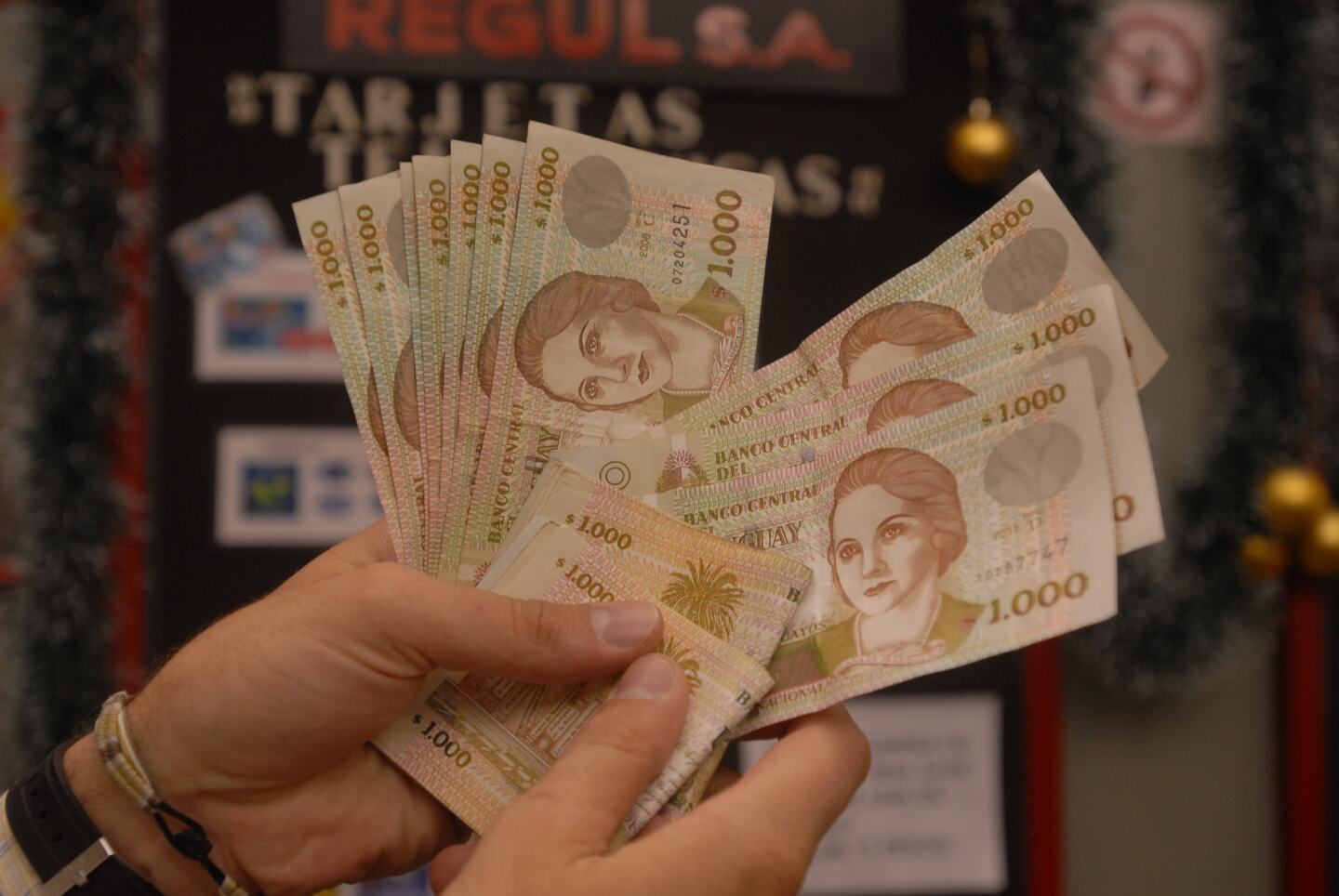 Persona contando billetes de pesos uruguayos.