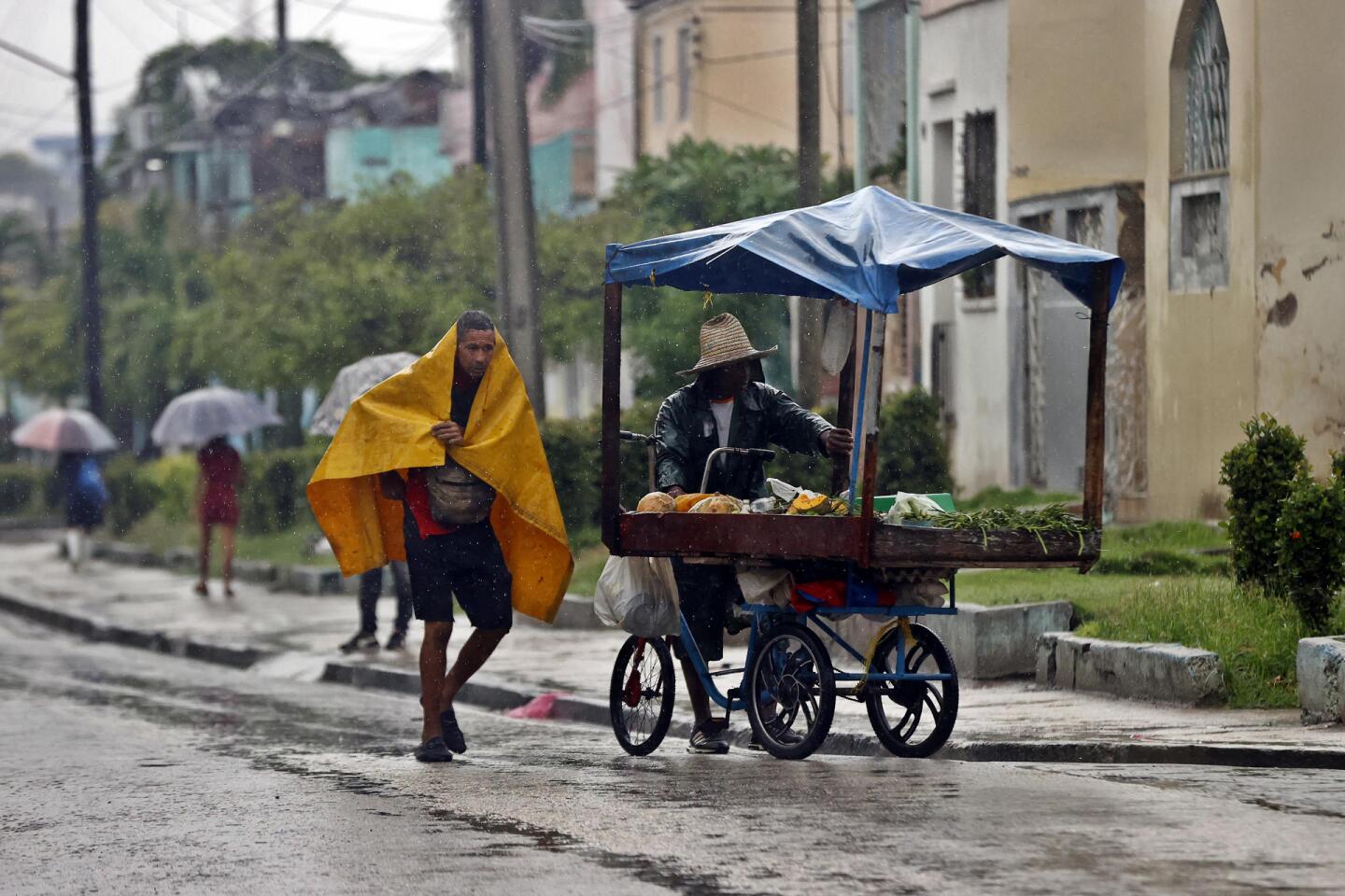 Personas se protegen de la lluvia este martes, en Santiago de Cuba (Cuba)