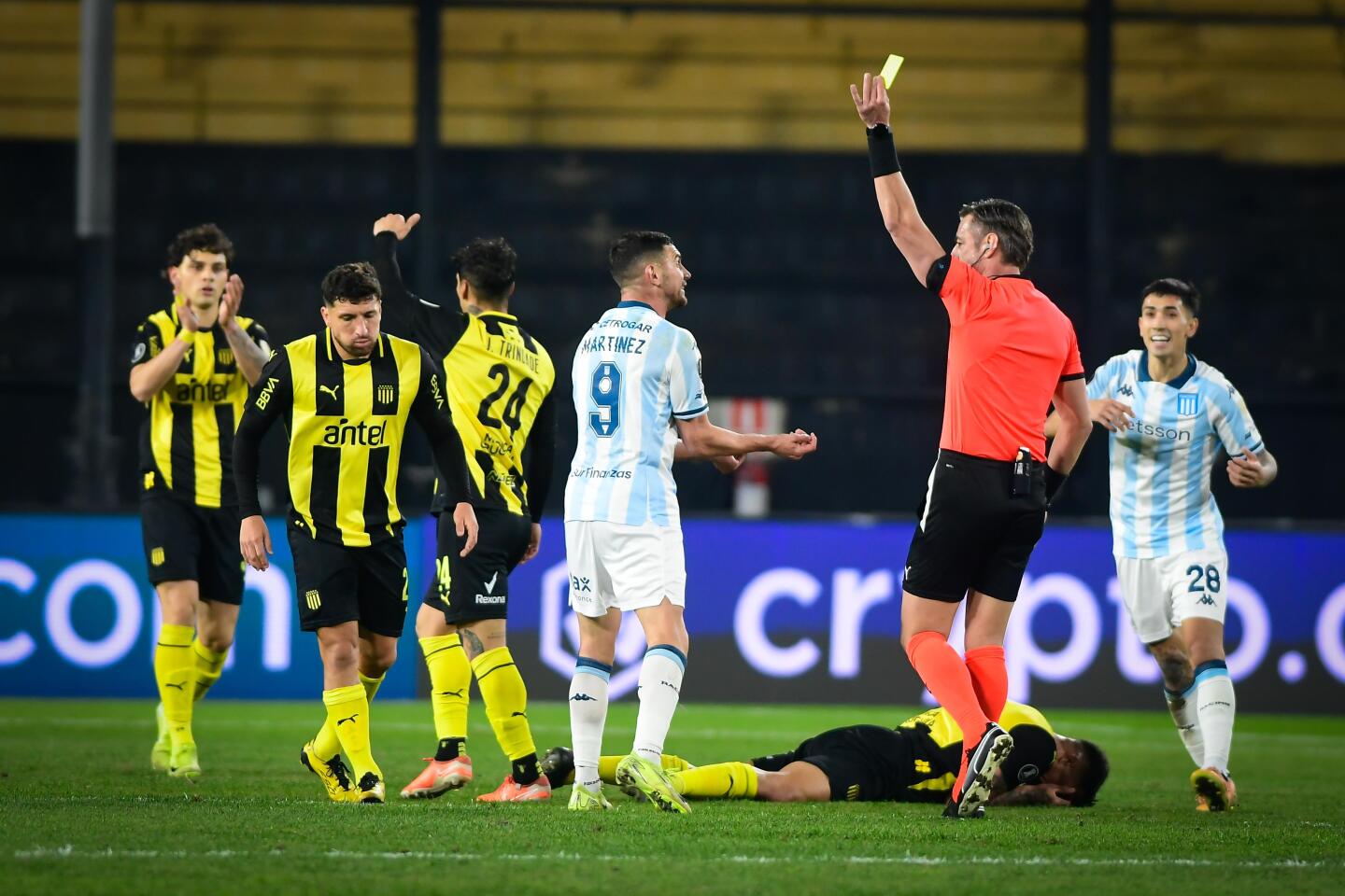 El árbitro Raphael Claus le muestra la tarjeta amarilla a Adrián Martínez, de Racing, ante Peñarol por Libertadores.