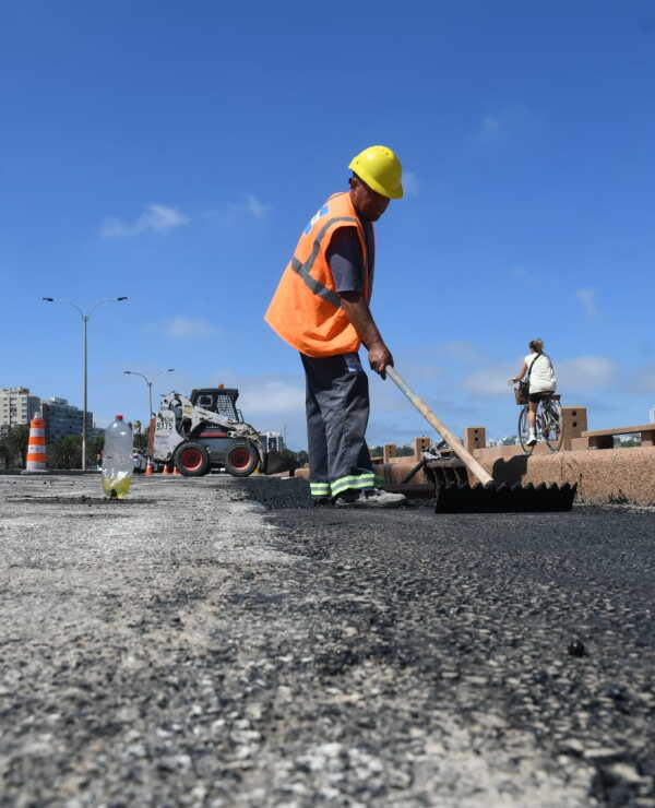 Funcionario con un rastrillo trabaja en la construcción de la ciclovía de la rambla de Montevideo.