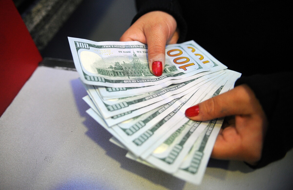 Persona contando billetes de 100 dólares estadounidenses.
