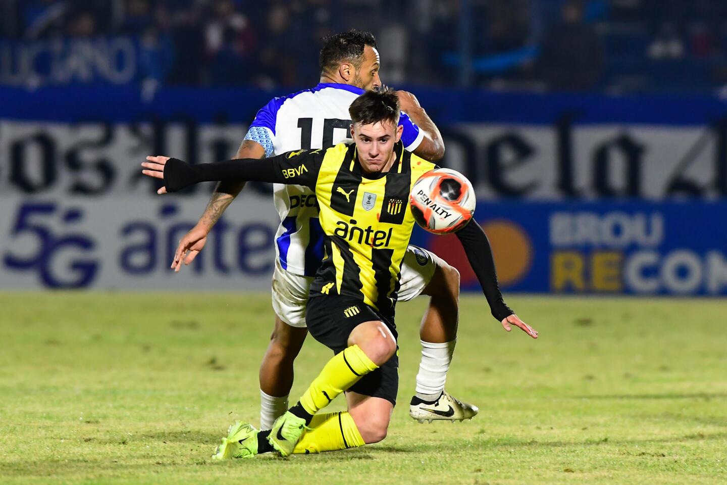 Sebastián Assis y Leandro Umpiérrez disputan la pelota en el partido entre Cerro Largo y Peñarol en el Estadio Ubilla.