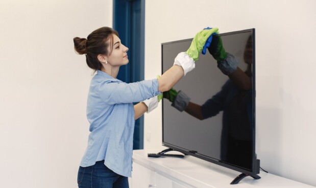 Una mujer limpiando un televisor.