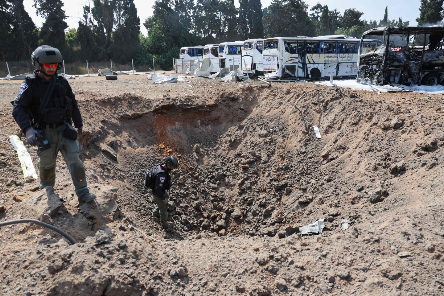Miembros de las fuerzas de seguridad israelíes inspeccionan un cráter en el lugar del impacto de un misil iraní en una estación de autobuses en Herzliya, cerca de Tel Aviv.