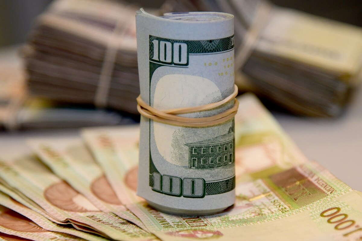 Billetes de dólares estadounidenses sobre otros de 1.000 pesos uruguayos.