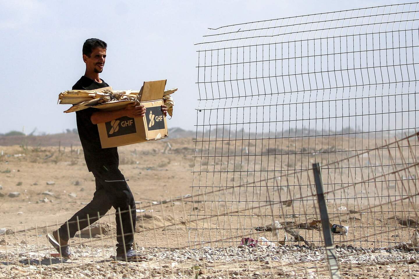 Un hombre camina con una caja de cartón que contiene la Fundación Humanitaria de Gaza