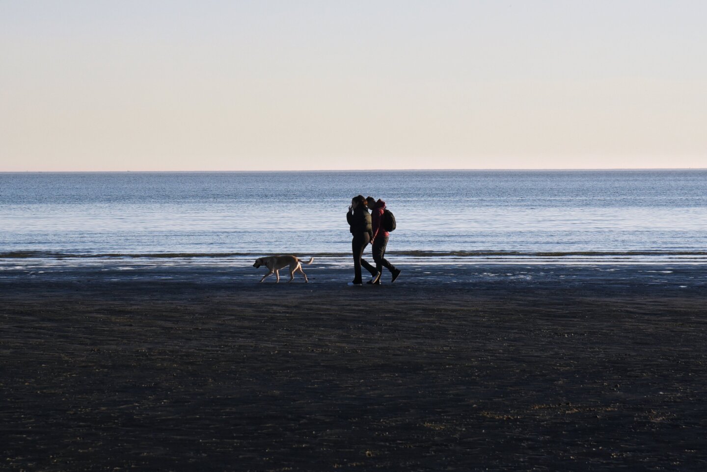 Personas caminando por una playa de Montevideo.