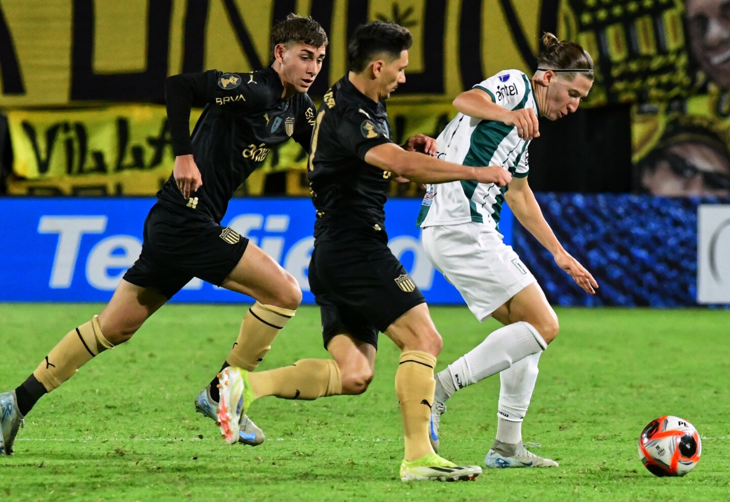 Bautista Tomatis ante la marca de Maximiliano Silvera y Juan Rodríguez en el partido entre Peñarol y Racing.