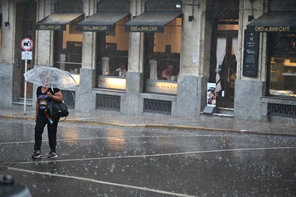 Una mujer cruza la calle con paraguas un día de lluvia en Montevideo.