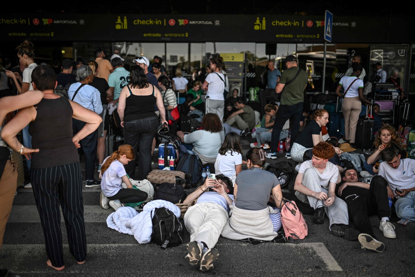 Personas con su equipaje esperan fuera del aeropuerto Humberto Delgado tras un apagón general en Lisboa el 28 de abril de 2025.