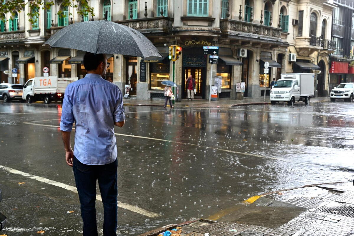 Un hombre cruza la calle con paraguas un día de lluvia en Montevideo.