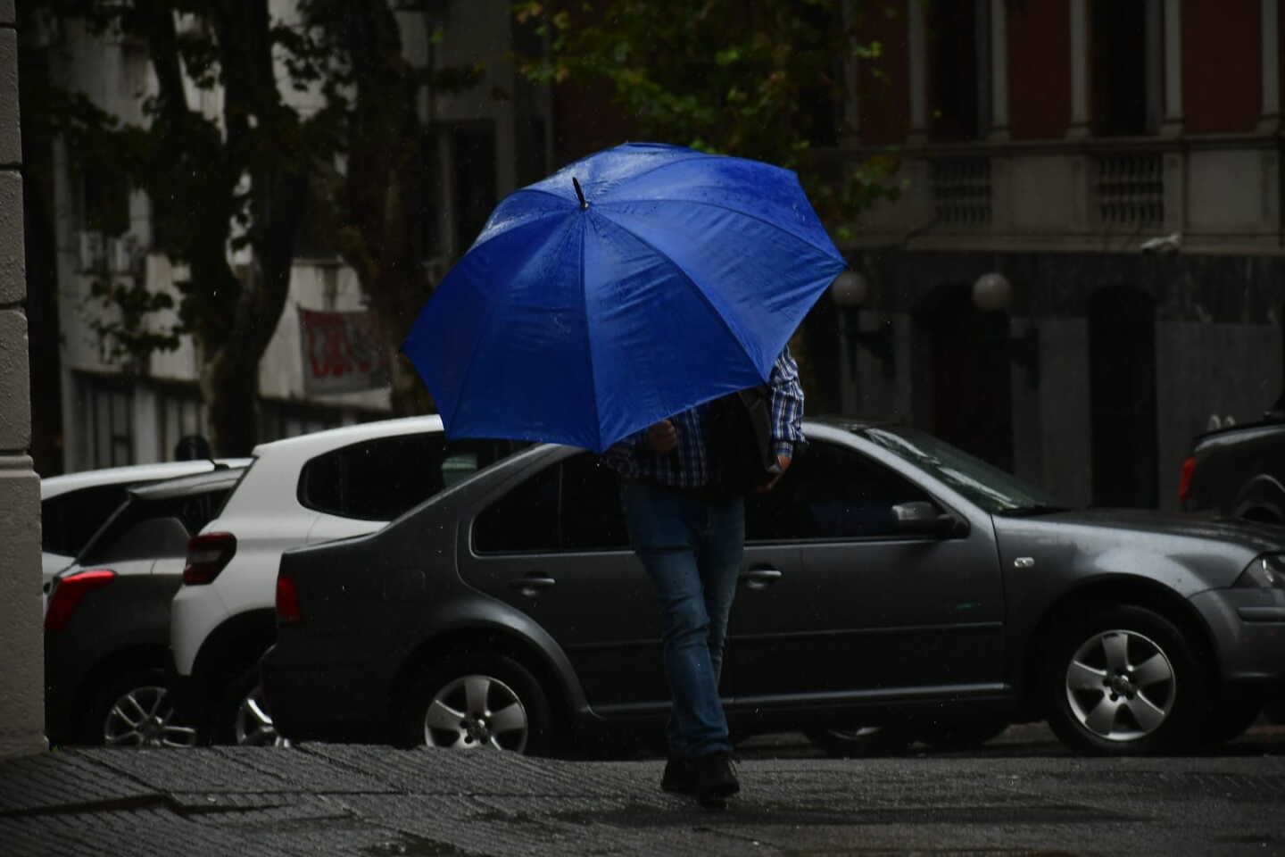 Un hombre camina con paraguas por Montevideo un día de lluvia.