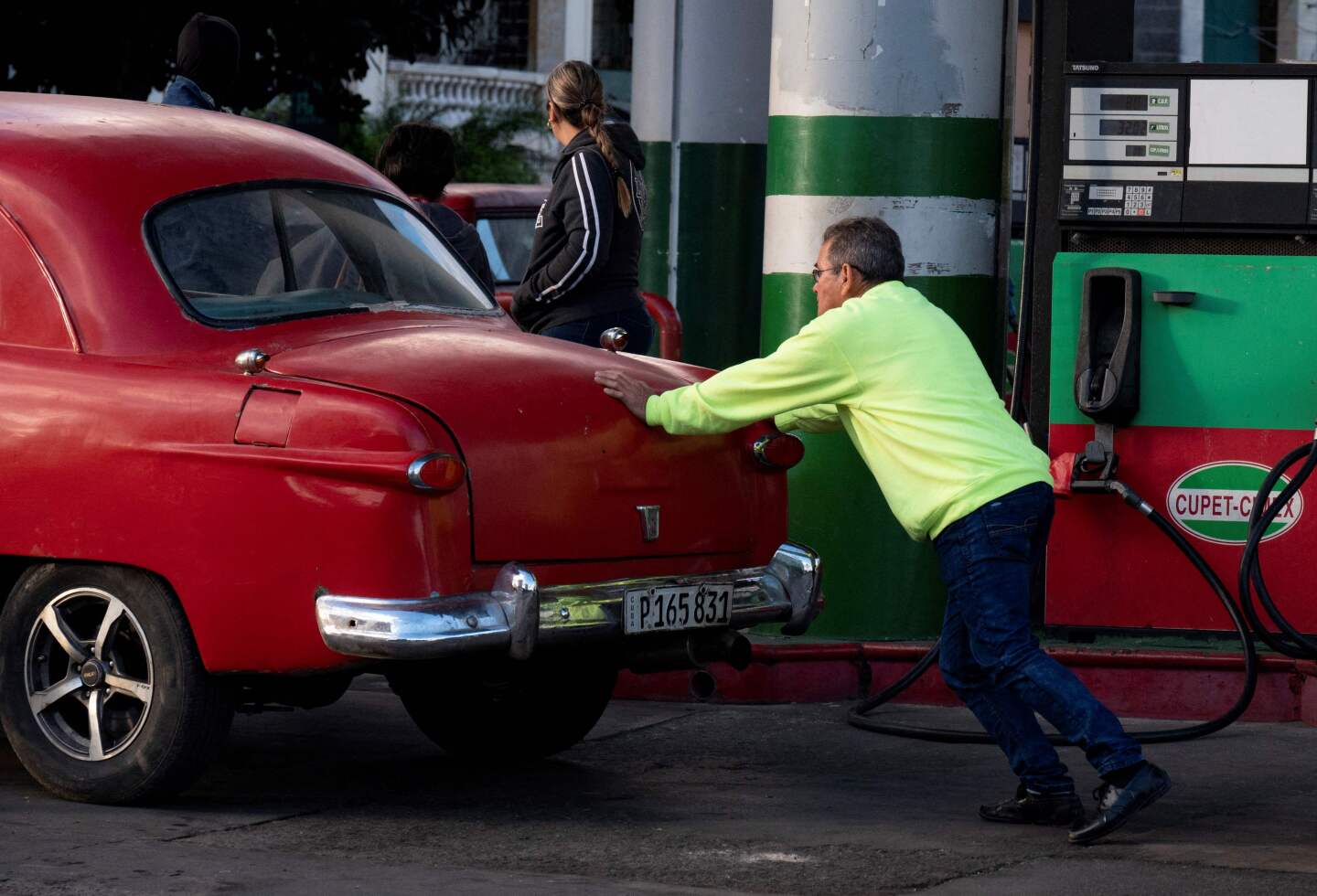 Un hombre empuja su vehículo en una estación de servicio tras una larga espera para cargar combustible
