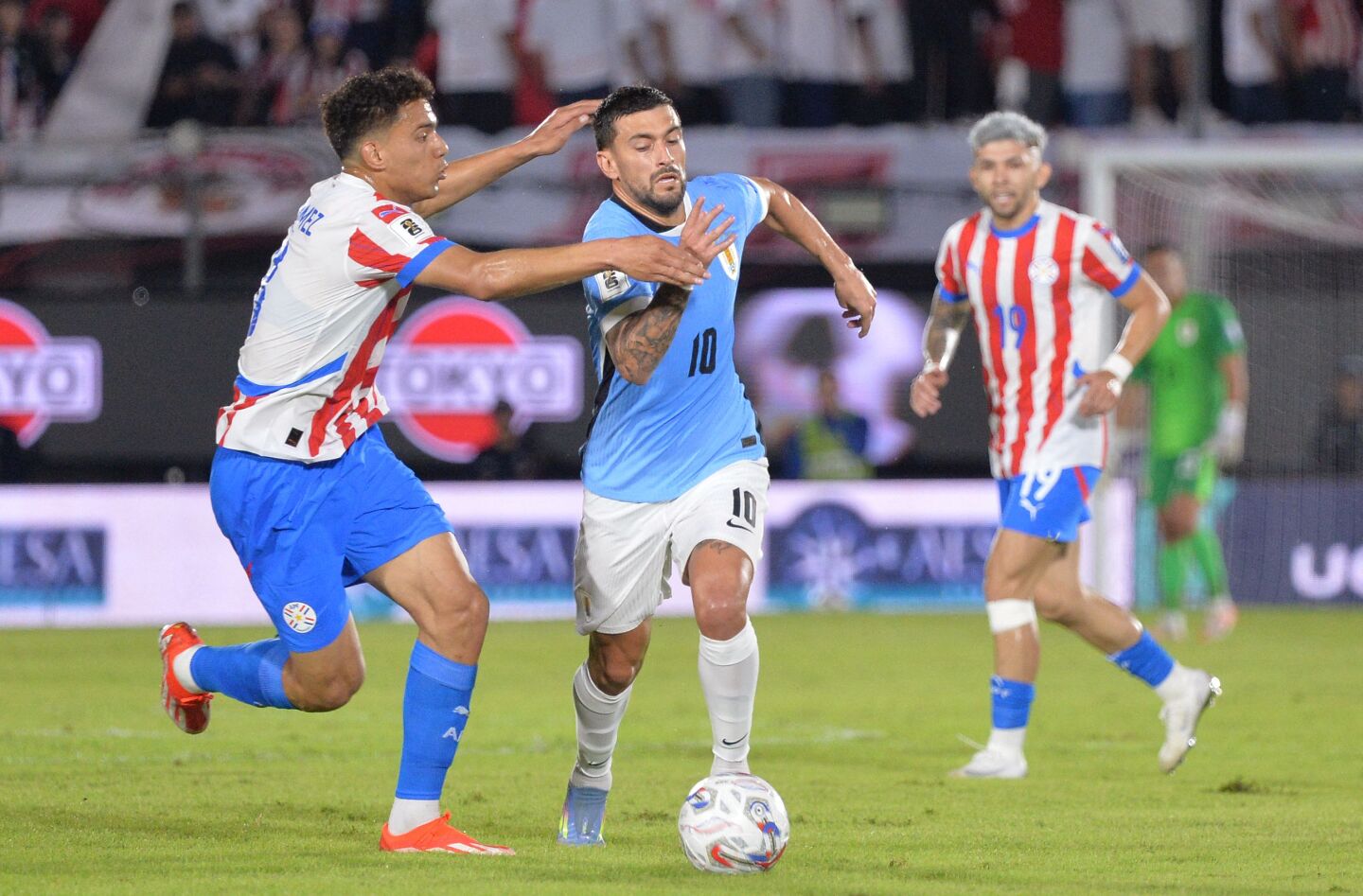 Giorgian de Arrascaeta ante la marca de Diego Gómez en el partido entre Paraguay y Uruguay por las Eliminatorias rumbo al Mundial 2026.
