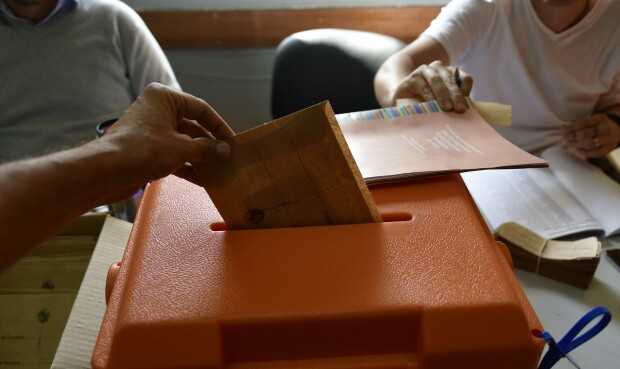 Una persona introduce un sobre de votación en una urna por las Elecciones Nacionales.
