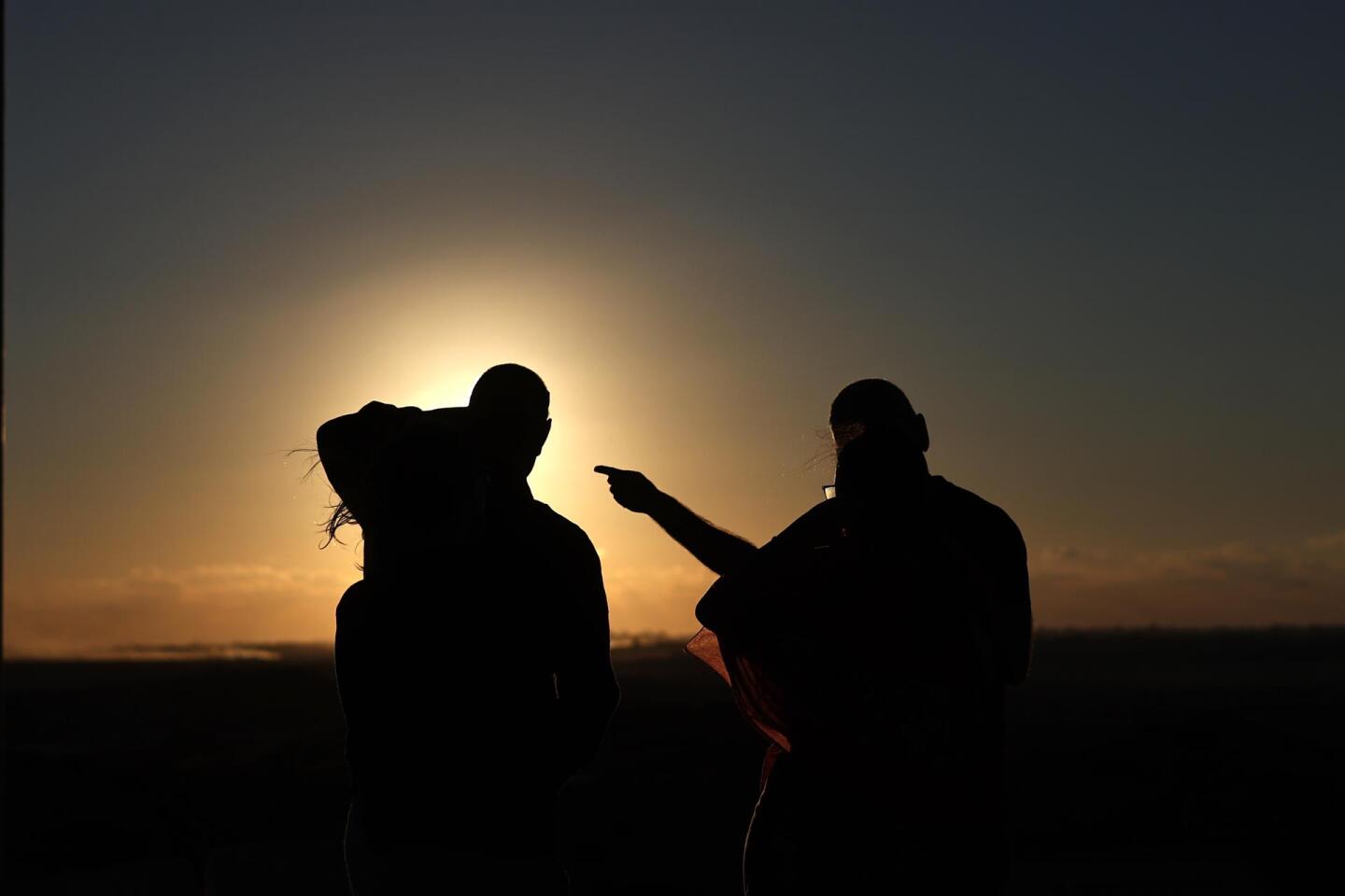 Dos israelíes observan la puesta de sol en la Franja de Gaza desde la ciudad de Sderot tras el acuerdo Israel-Hamas.