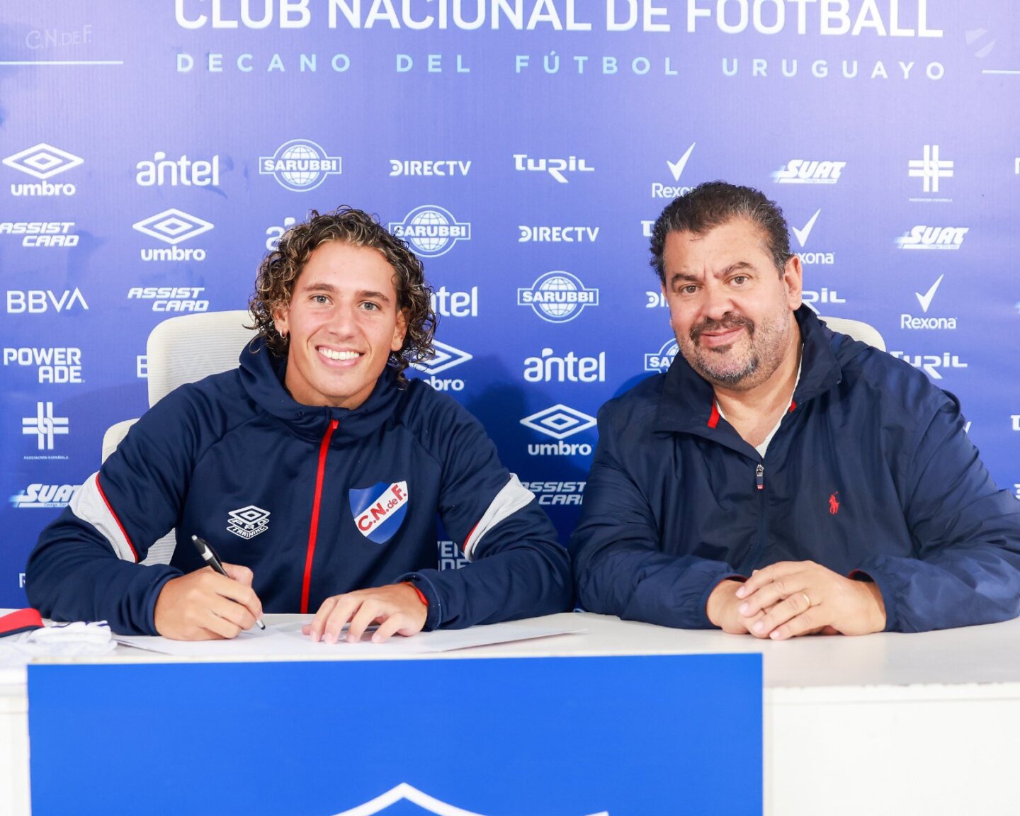 Luciano Boggio firmando contrato en Nacional junto a Flavio Perchman.