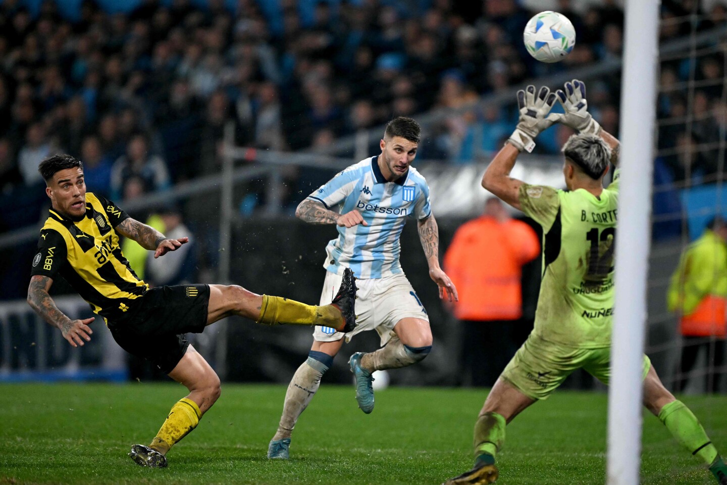 Franco Pardo gana de cabeza para el tercer gol de Racing ante Javier Méndez y Brayan Cortés.