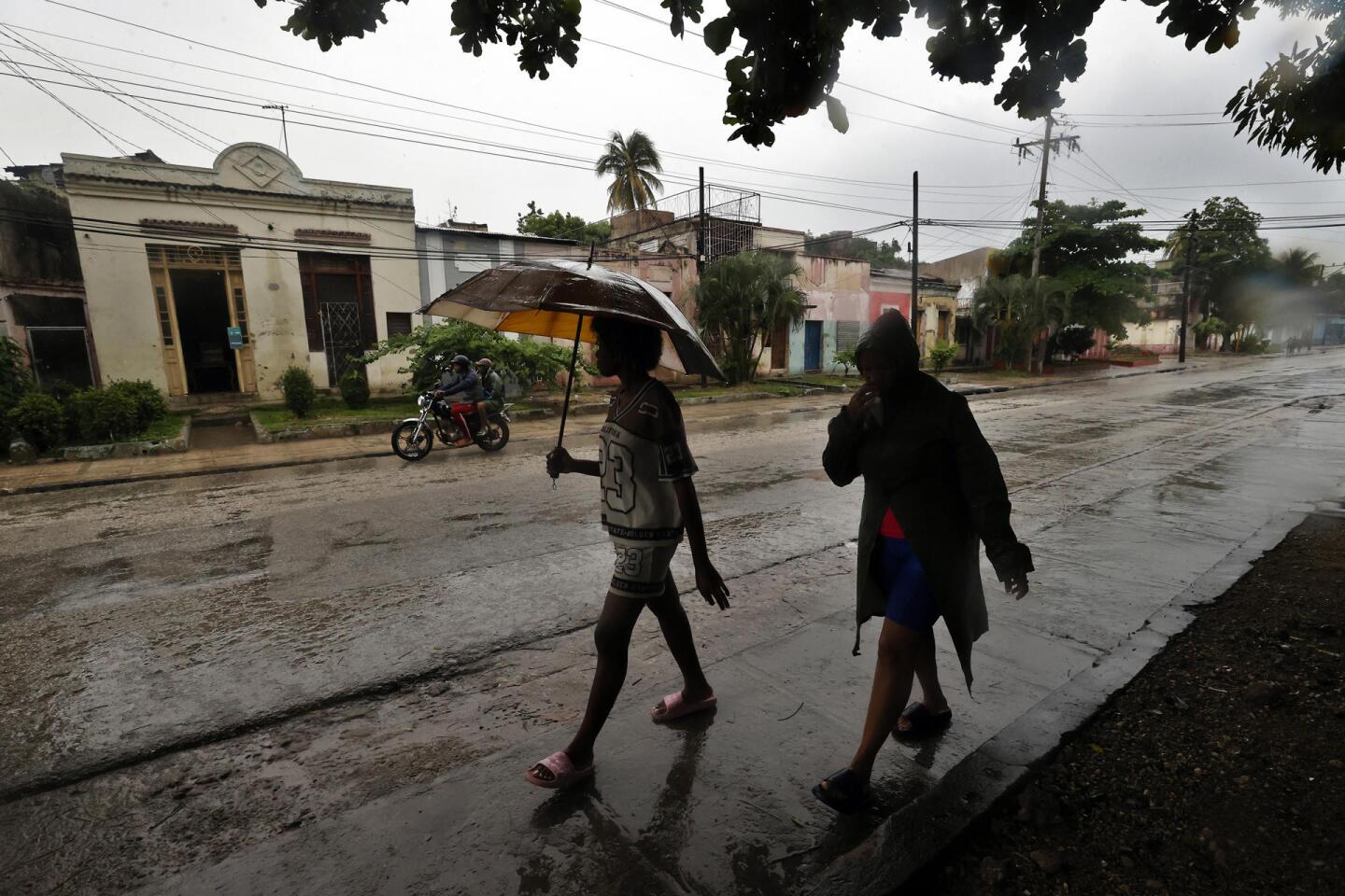 Personas caminan por las calles de Cuba cubriéndose de la lluvia previo a la llegada del huracán Melissa.