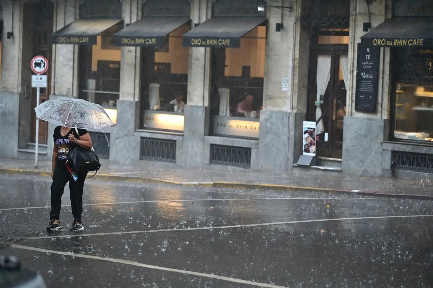 Una mujer cruza la calle con paraguas un día de lluvia en Montevideo.