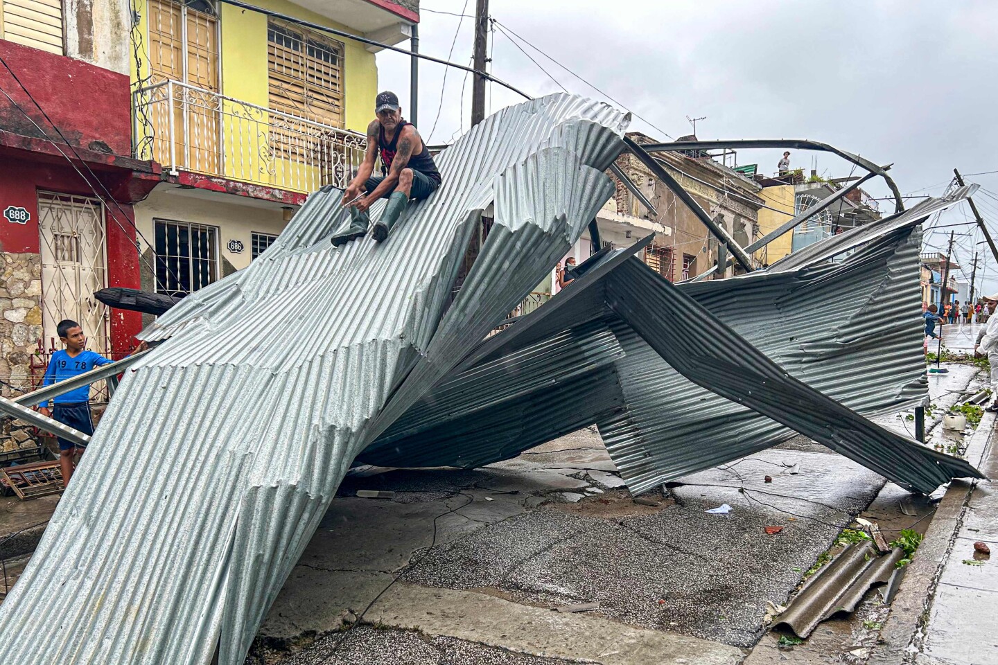 Un residente se sienta en parte del techo de su casa, dañada por el huracán Melissa, en Santiago de Cuba el 29 de octubre de 2025.